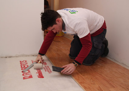 A volunteer is laying flooring in a Halsey Street residential building. Photo courtesy of Habitat for Humanity-NYC.