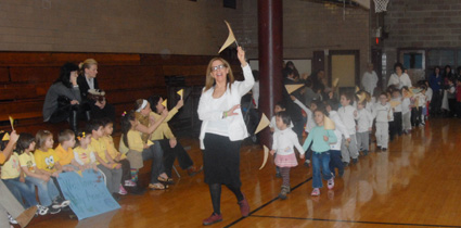 Teacher Mary Brannan leads the Pre-K students on a flag-waving march around the gym.