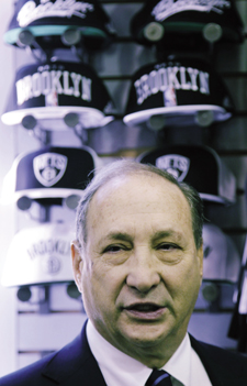 Bruce Ratner, standing in front of a display of Nets caps