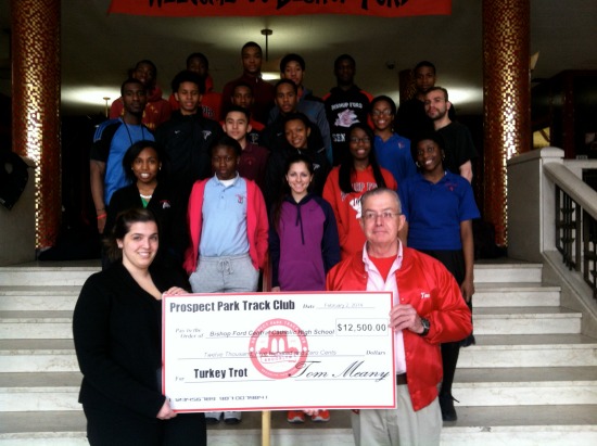 Tom Meany of the Prospect  Park Track Club, presents Denise Catapano, assistant director of athletics at Bishop Ford, with a check for the school. Members of the boys and girls track teams were on hand for the presentation. Photo courtesy of Bishop Ford Central Catholic High School.