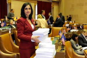Assemblywoman Nicole Malliotakis shows a stack of bills in the assembly chamber to illustrate how the State Legislature wastes paper. Photo courtesy of Malliotakis’s office