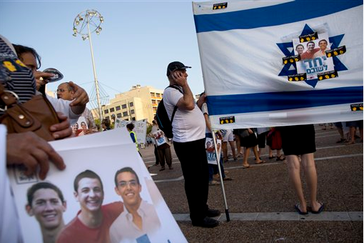 Israelis hold the national flag with a photo of the missing three boys who have now been confirmed as dead