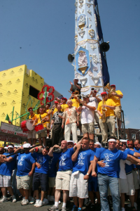 Paranzas (lifters) raise the Giglio, which holds an orchestra, emcee and parish priest
