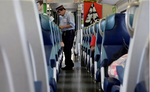 A conductor punches tickets aboard the Long Island Rail Road. Conductors like him may strike on Sunday