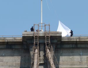 NYPD ESU officers take white flag down from Brooklyn Bridge. Photo by Mary Frost
