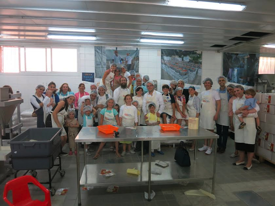 Joseph Ezon (front row eighth from right) and members of his extended family packed food for needy families in Israel during a visit to Pantry Packers, a charity program in Jerusalem