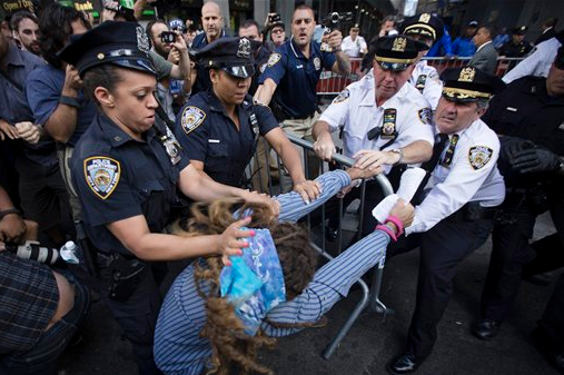 Protestors and police wrestle with a barricade on the corner of Wall Street and Broadway during a march demanding action on climate change and corporate greed, on Monday.