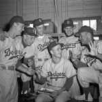 In this 1954 photo provided by the Brooklyn Dodgers, pitcher Ed Roebuck hands out cigars on the birth of his son. With him, left to right, are teammates Don Zimmer, Johnny Podres, George Shuba, Dick Williams and Roy Campanella, who holds up six fingers to remind Roebuck that he has six children. The Los Angeles Dodgers said George "Shotgun" Shuba died Monday. He was 89.