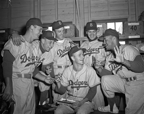 In this 1954 photo provided by the Brooklyn Dodgers, pitcher Ed Roebuck hands out cigars on the birth of his son. With him, left to right, are teammates Don Zimmer, Johnny Podres, George Shuba, Dick Williams and Roy Campanella, who holds up six fingers to remind Roebuck that he has six children. The Los Angeles Dodgers said George "Shotgun" Shuba died Monday. He was 89.