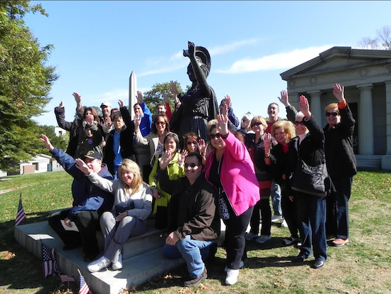 Members of the tour group strike the same pose as the statue of Minerva, who stands at the highest point in Green-Wood Cemetery and seemingly waves hello to the Statue of Liberty in New York Harbor. Eagle photo by Paula Katinas