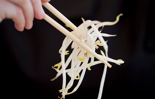 In this June 5, 2011 file photo, a woman holds bean sprouts with chopsticks in Berlin, Germany. Raw sprouts are again linked to dozens of cases of food poisoning. The Centers for Disease Control and Prevention says 63 people from 10 states concentrated on the East Coast fell ill with salmonella linked to bean sprouts from a supplier in New York City. AP Photo/Gero Breloer