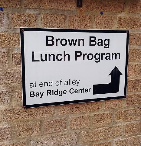 This sign points the way to the Bay Ridge Center’s brown bag lunch program. Photo by Stephanie Kotsikonas