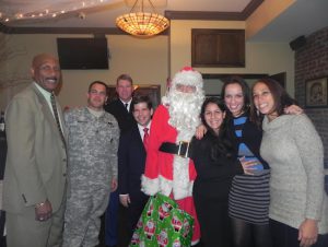 Santa Claus (AKA Eagle columnist Charles Otey) and Councilmember Vincent Gentile (fourth from left) enjoy the party with Fort Hamilton commander Col. Joseph Davidson (third from left), fort personnel, and members of military families. Eagle photos by Paula Katinas