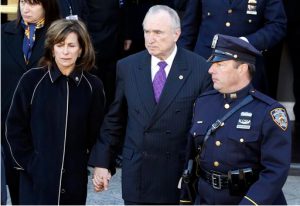 New York Police Department commissioner William Bratton, center, walks with his wife Rikki Klieman, left, following funeral services for officer Rafael Ramos. AP Photo/Julio Cortez