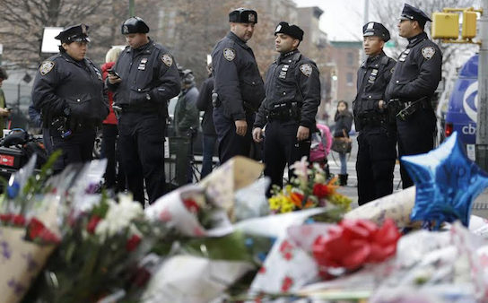 Police officers gather near a makeshift memorial near the site where fellow officers Rafael Ramos and Wenjian Liu were murdered. Police say Ismaaiyl Brinsley ambushed the two officers in their patrol car in broad daylight Saturday, fatally shooting them before killing himself inside a subway station. AP Photo/Seth Wenig