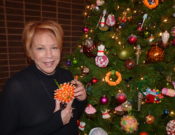 Pamela Harwood stands beside the eye-catching Christmas tree in the lobby of a Brooklyn Heights co-op. She created the candy ornaments on the tree and led a holiday workshop for kids. Photo by Mary Frost