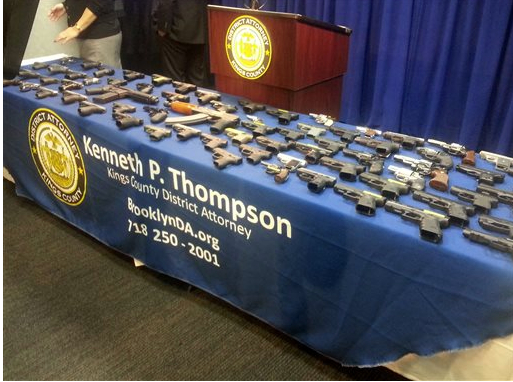 In this photo provided by the Brooklyn District Attorney's Office, a collection of handguns and two assault rifles fill a table during a news conference at the Brooklyn District attorney's Office, on Tuesday. AP Photo/Brooklyn District attorney's Office, Christina Carrega-Woodby