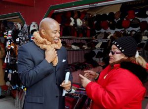 Brooklyn Borough President Eric L. Adams tries on a scarf at the inaugural Holiday Market Village in Columbus Park, which he launched with the Congress of Racial Equity (CORE), who is organizing and operating the effort. Photo Credit: Kathryn Kirk/Brooklyn BP’s Office