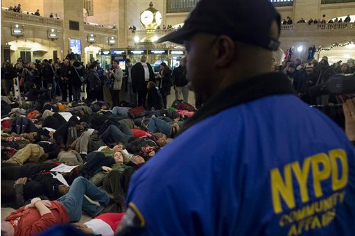 Police officers stand guard as protestors participate in a "die-in" at Grand Central Station during a demonstration against a grand jury's decision not to indict the police officer involved in the death of Eric Garner, on Saturday. AP Photo/John Minchillo