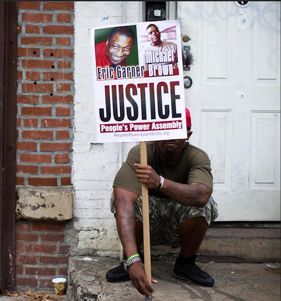 A demonstrator holds a sign bearing the likeness of Staten Island’s Eric Garner and Ferguson’s Michael Brown before a march to protest the death of Garner on Saturday in Staten Island. AP Photo/John Minchillo