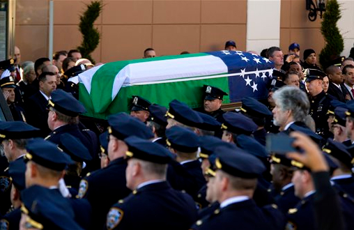 The body of New York City police officer Rafael Ramos is brought from Christ Tabernacle Church draped in an NYPD flag after his funeral in the Glendale section of Queens, where he was a church member, Saturday, Dec. 27, 2014, in New York. Ramos and his partner, officer Wenjian Liu, were killed Dec. 20 as they sat in their patrol car on a Brooklyn street. AP Photo/Craig Ruttle