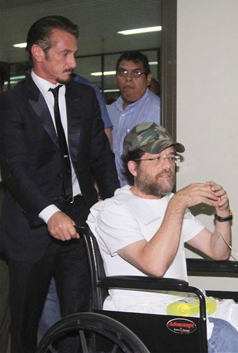 In this 2012 file photo, actor Sean Penn pushes U.S. businessman Jacob Ostreicher in a wheelchair, during a recess at Ostreicher's hearing in Santa Cruz, Bolivia. AP Photo, File
