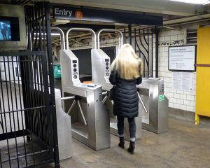 On Thursday, the MTA board approved subway, bus and toll fare hikes, which will take effect in March. Shown: A subway rider swipes her MetroCard at the F train stop in DUMBO. Photo by Mary Frost