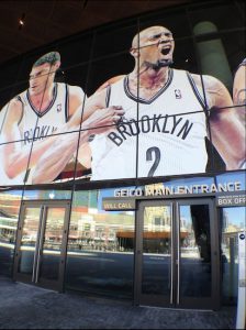 It looks like Nets player Kevin Garnett, depicted over the entrance to Barclays Center, is tearing his shirt in despair because the Democrats are not bringing the 2016 convention to Brooklyn. Photos by Lore Croghan