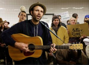 Andrew Kalleen joins other performers during a protest in the Metropolitan Avenue Subway station on Oct. 21, 2014, in New York. Kalleen, 30, was performing Friday, Oct. 17 at the G-train stop in Williamsburg when an officer told him he must leave the station because he needs a permit to play there. AP Photo/Frank Franklin II