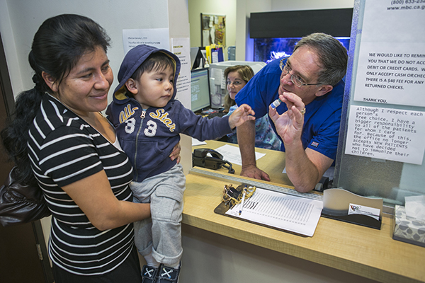 Pediatrician Charles Goodman talks with mom Carmen Lopez, 37, holding her 18-month-old son, Daniel after being vaccinated with the measles-mumps-rubella vaccine at his office in California, where the current outbreak began. AP Photo by Damian Dovarganes