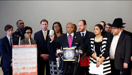 Brooklyn Borough President Eric L. Adams holds up a smoke detector next to his poster on fire safety essentials as he announced a borough-wide fire safety education campaign called for the creation of a burn center in Brooklyn. Photo courtesy of Adams' office