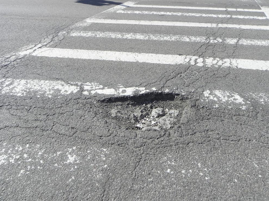 Community Board 10 staff members reported 53 potholes and street cave-ins in the space of a single month. This pothole was found on Fourth Avenue. Eagle photo by Paula Katinas