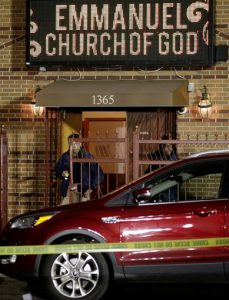 A New York City police detective investigates the scene of a shooting in which two people were killed and three others wounded outside Emmanuel Church of God in Brooklyn early Tuesday. Police said a wake was being held in the church at the time of the shooting. AP Photo/Kathy Willens