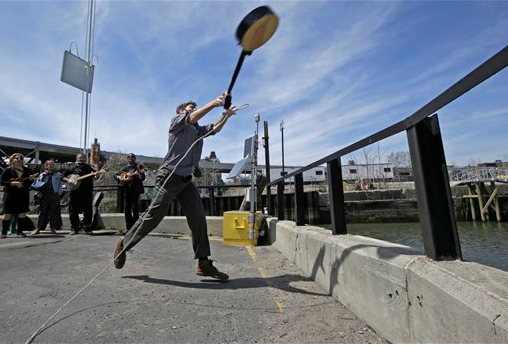 Event founder, banjo player and folk music promoter Eli Smith tosses a banjo during the fifth annual Brooklyn Folk Festival's Gowanus Banjo Toss, on Sunday in Brooklyn. About two dozen people participated in the annual event. Smith who conceived the event said, "I love the banjo, but sometimes I have the perverse desire to see it thrown into a body of water." AP Photo/Kathy Willens