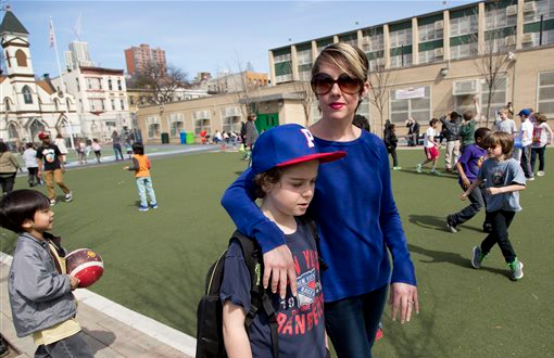 Kristen Couse walks with her son, Wile, on the playground at Public School 261 on Thursday in Brooklyn. According to Couse her fifth-grade son and the majority of his classmates are opting-out of a state-mandated testing program. Some New York school districts are reporting that 60 to 70 percent of students boycotted this week's statewide English tests. AP Photos/Mark Lennihan