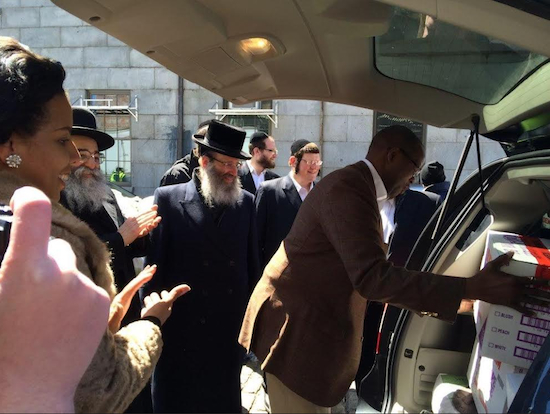 Brooklyn District Attorney Ken Thompson offers a helping hand at the pre-Passover food distribution on Sunday. At left is Councilmember Laurie Cumbo. Photo courtesy UJO of Williamsburg and North Brooklyn