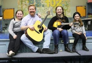 Volunteer Brian Doherty and his daughters get set to enjoy a talent show at P.S. 102. Photo courtesy of Learning Leaders