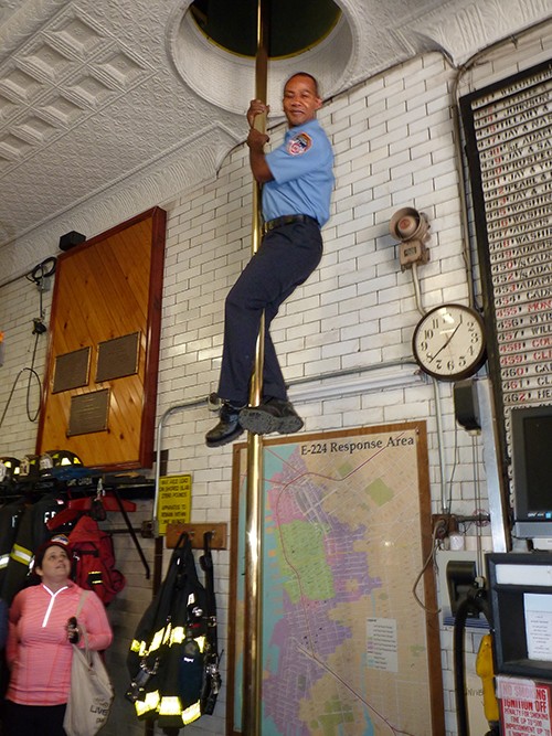 Firefighter Coombs slides down the fire pole like greased lightning. Photo by Mary Frost