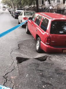 A few more feet to the right and the sinkhole would have swallowed the car parked on Bay Ridge Parkway. Photo by John Quaglione