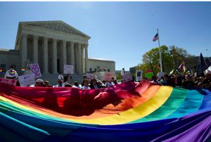 In this April 28 file photo, demonstrators stand in front of a rainbow flag of the Supreme Court in Washington. The Supreme Court just ruled that same-sex couples can marry anywhere in the United States. AP Photo/Jose Luis Magana, File