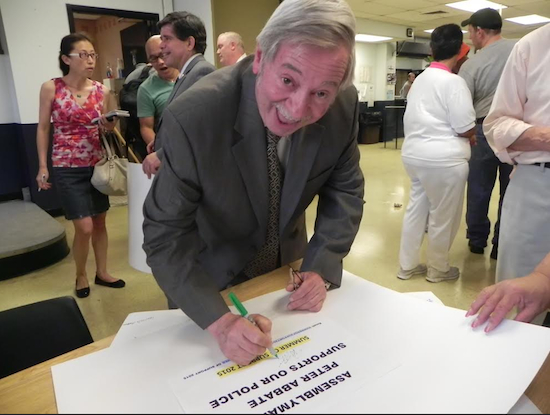 Assemblymember Peter Abbate signs a message board and says he will display a board at his district office for others to sign. Eagle photo by Paula Katinas