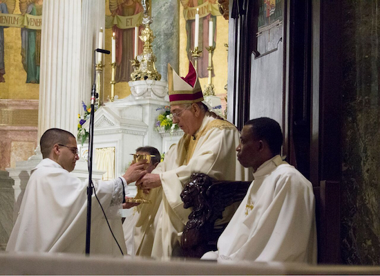 Fr. Rafael Perez (kneeling) accepts a chalice from Bishop Nicholas DiMarzio during the ordination liturgy. Brooklyn Eagle Photo by Francesca N. Tate