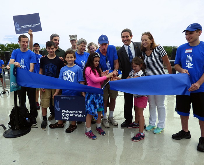 Officials and children cut the blue ribbon to officially kick off 2015’s City of Water Day. Shown (center with scissors) Roland Lewis, president of the Waterfront Alliance, assisted by New York City Councilmember Ben Kallos. Photo by Mary Frost
