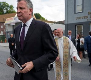 New York City Mayor Bill de Blasio walks to a memorial service for Eric Garner at the Mount Sinai United Christian Church in Staten Island on Tuesday, just short of a year after Garner died while being taken into custody by NYPD officers. A $5.9 million settlement in Garner's death, a black man who died after being placed in a white police officer's chokehold, was reached with the city this week, days before the anniversary of his death. AP Photo/Craig Ruttle