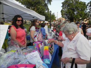 Josephine Beckmann (left), a member of the 68th Precinct Community Council, works the raffle booth at last year’s Night Out Against Crime event in Shore Road Park. Dozens of prizes were given away. Eagle file photo by Paula Katinas