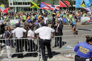 New York City Police officers study the scene of a fatal stabbing at Grand Army Plaza on Monday as participants in the West Indian Day Parade pass behind them. Earlier in the day, a man was stabbed to death at the location and an aide to Gov. Andrew Cuomo was shot in the head. AP Photo/Mark Lennihan