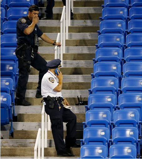 NYPD officers investigate the southwest corner of Louis Armstrong Stadium after a drone flew over the court, buzzing the players during a match between Flavia Pennetta, of Italy, and Monica Niculescu, of Romania, during the second round of the U.S. Open tennis tournament on Thursday. The drone crashed into the seats and can be seen to the right of the police officer on his phone. AP Photo/Kathy Willens