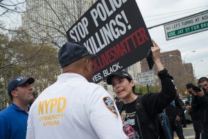 Attorney Gretchen Kleinman, carrying a poster reading “Stop Police Killings!” stood just inches from PBBN Community Affairs Lieutenant Marvin Luis during a confrontation which took place at Thursday’s anti-police violence rally in Downtown Brooklyn. Photo by Albin Lohr Jones