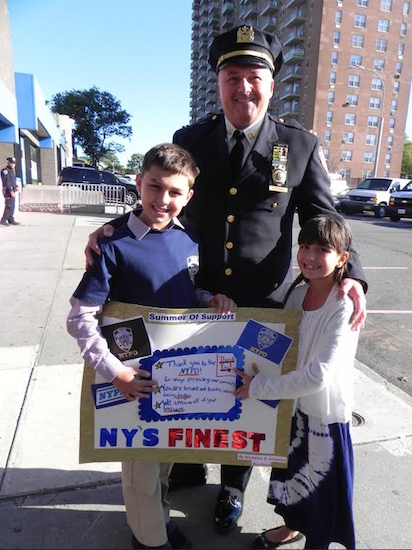 Capt. Ray Festino, commanding officer of the 68th Precinct accepts a handmade poster from two of his biggest fans, Nicholas and Julianna Bambina. Eagle photos by Paula Katinas