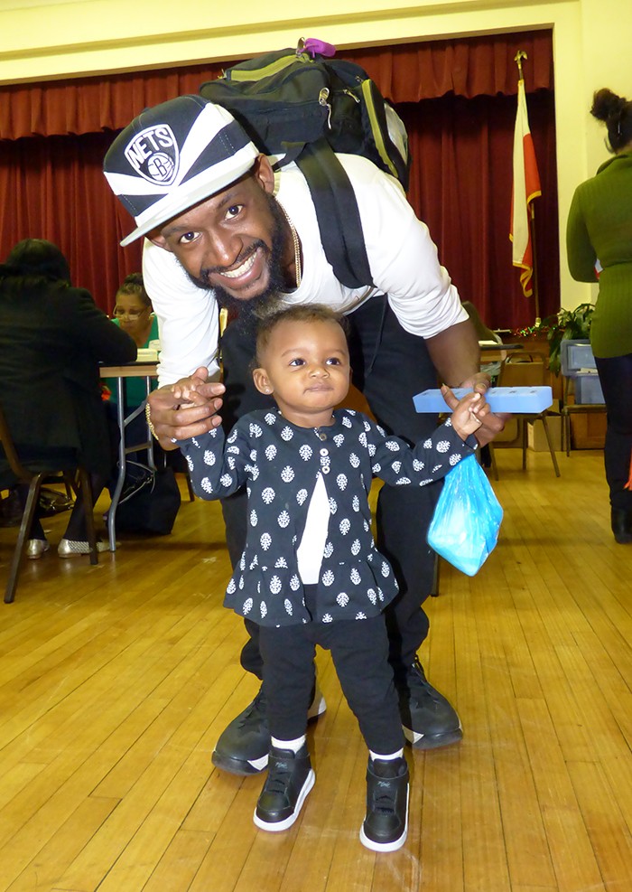Gamal Morton, who works with CUNY Services, holds Saturday’s smaller volunteer – Elleira, 11 months old. Photos by Mary Frost